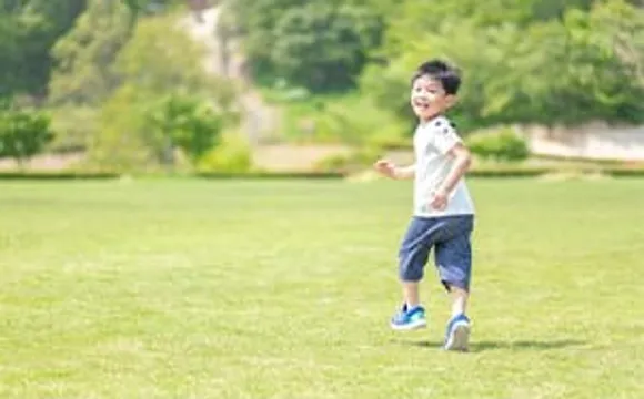 芝生の広場を笑顔で走る男の子