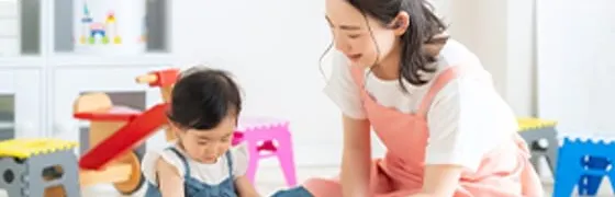 保育士と幼児が積み木で遊ぶ様子