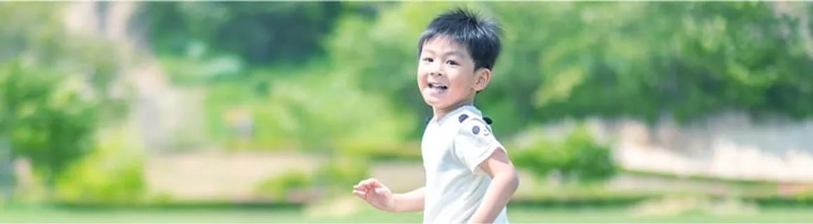 緑の中を笑顔で走る男の子