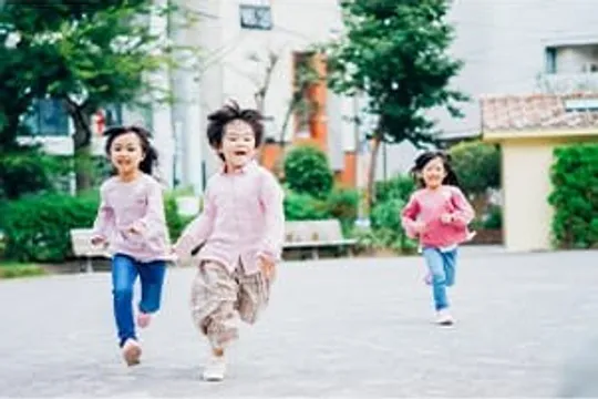 広場を笑顔で走る3人の子ども