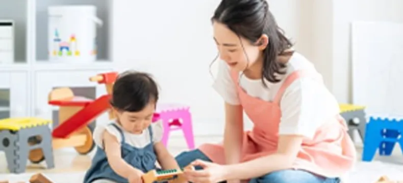 保育士と幼児が積み木で遊ぶ様子