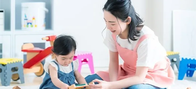 保育士と幼児が積み木で遊ぶ様子