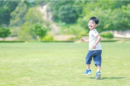 芝生の広場を笑顔で走る男の子