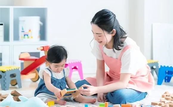 保育士と幼児が積み木で遊ぶ様子